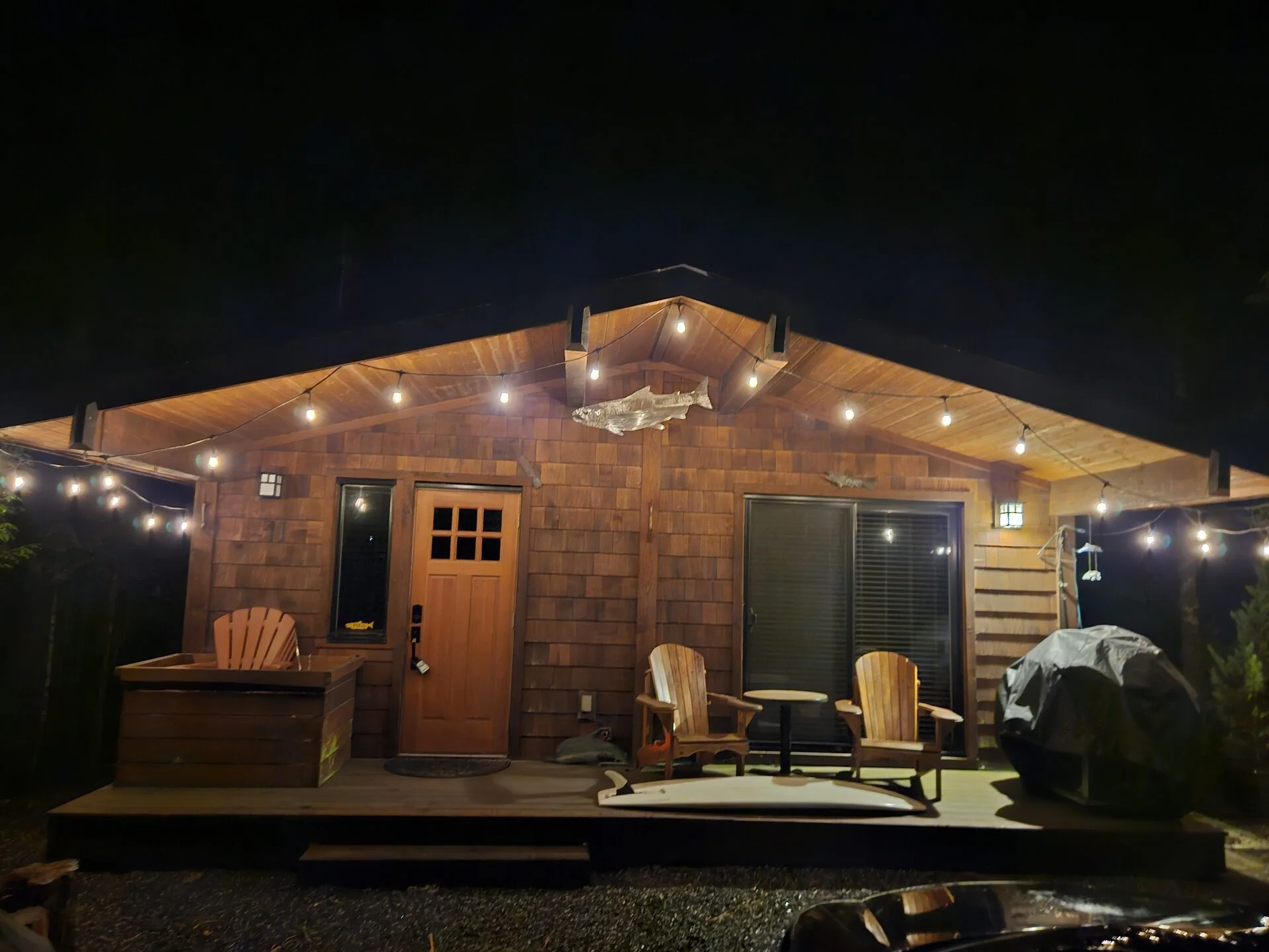 Rachael's Retreat cedar cabin glowing with string lights in the rainforest at night Port Renfrew BC